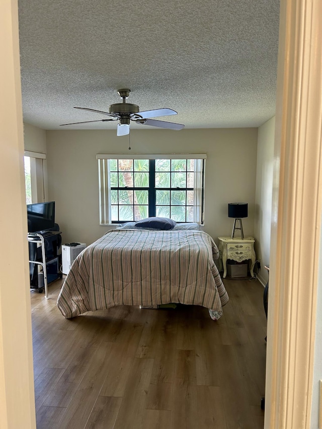6001 SE Landing Way Unit 10, Stuart, FL 34997 - bedroom featuring multiple windows, wood finished floors, a ceiling fan, and a textured ceiling