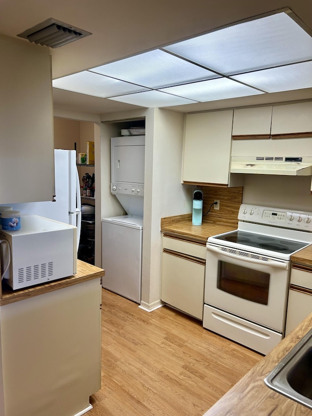 6001 SE Landing Way Unit 10, Stuart, FL 34997 - kitchen with white appliances, estacked washer and dryer, under cabinet range hood, light wood-style floors, and white cabinetry