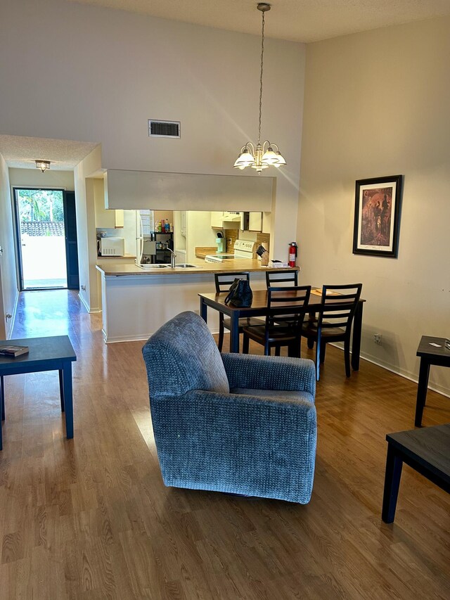 6001 SE Landing Way Unit 10, Stuart, FL 34997 - living room with a chandelier, wood finished floors, high vaulted ceiling, and baseboards
