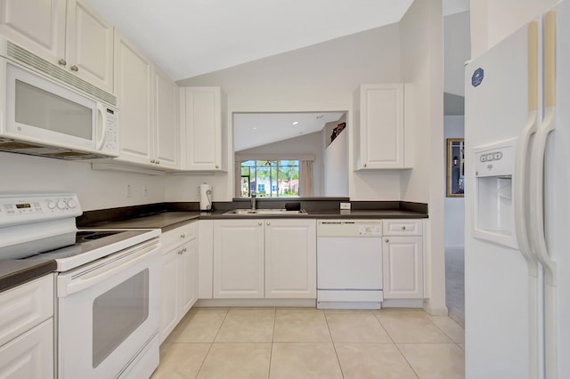 kitchen featuring white appliances, dark countertops, a sink, vaulted ceiling, and light tile patterned floors