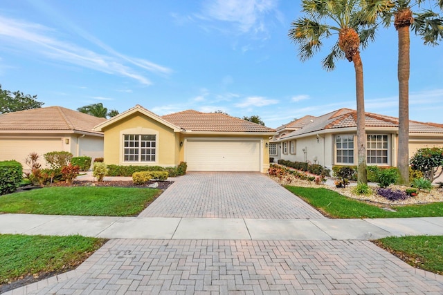view of front of house with stucco siding, a tiled roof, driveway, a front lawn, and a garage
