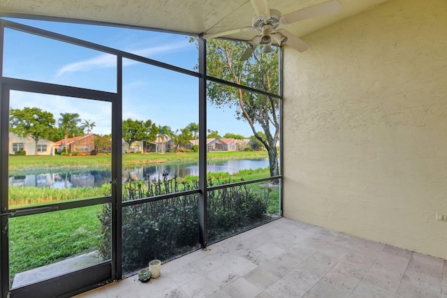 unfurnished sunroom with a water view and ceiling fan