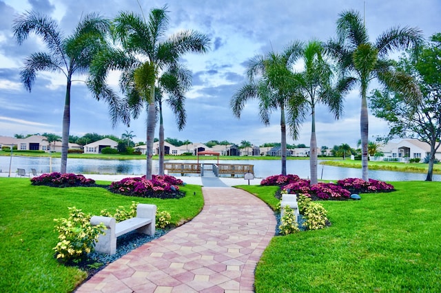 surrounding community featuring a lawn, a water view, and a dock