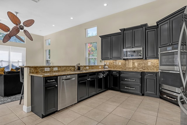8888 Rockridge Glen Cv, Boynton Beach, FL 33473 - kitchen featuring light tile patterned flooring, a sink, dark cabinetry, a peninsula, and stainless steel appliances