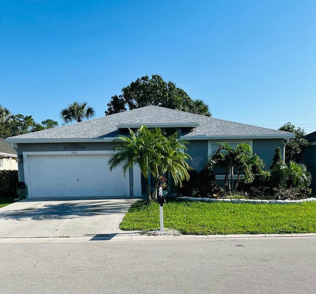 ranch-style home featuring stucco siding, a garage, concrete driveway, a front lawn, and roof with shingles