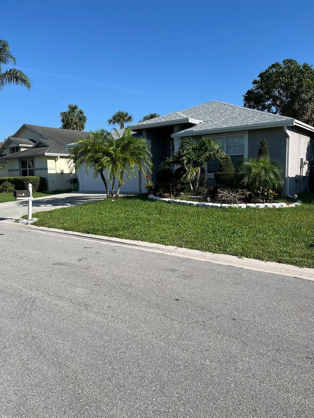single story home with stucco siding, a front yard, concrete driveway, and a garage