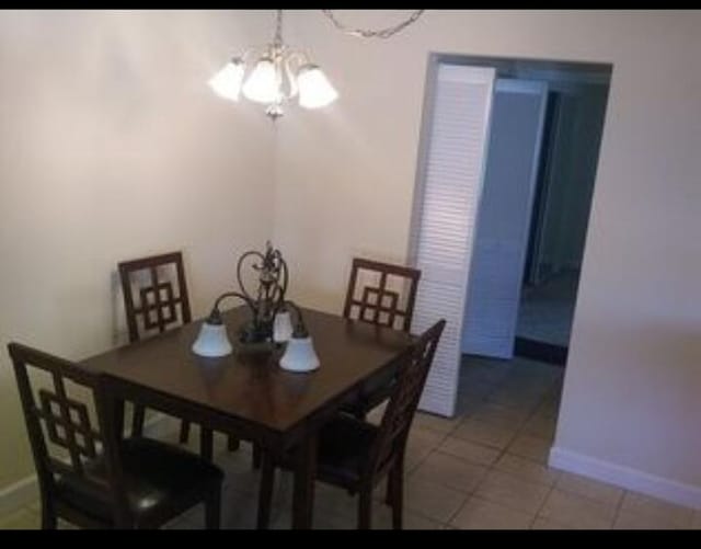 6020 Indrio Rd Unit 6, Fort Pierce, FL 34950 - dining area with baseboards, light tile patterned floors, and an inviting chandelier