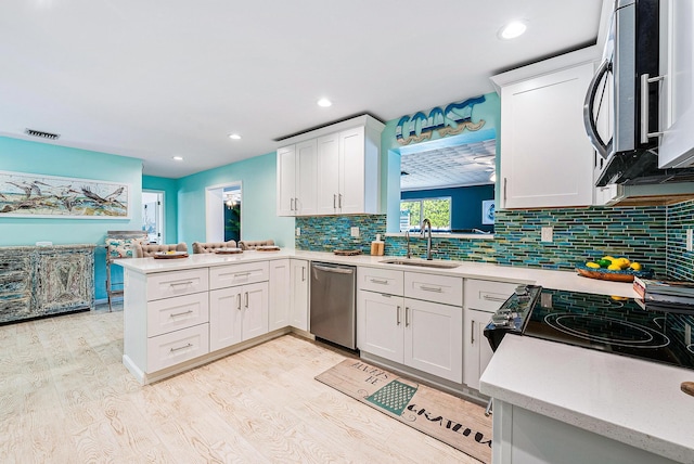 14283 Joan Dr, Palm Beach Gardens, FL 33410 - kitchen with stainless steel dishwasher, a peninsula, light wood finished floors, decorative backsplash, and white cabinets