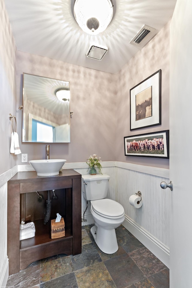 2990 Twin Oaks Way, Wellington, FL 33414 - half bathroom featuring visible vents, toilet, stone finish floor, a wainscoted wall, and a sink