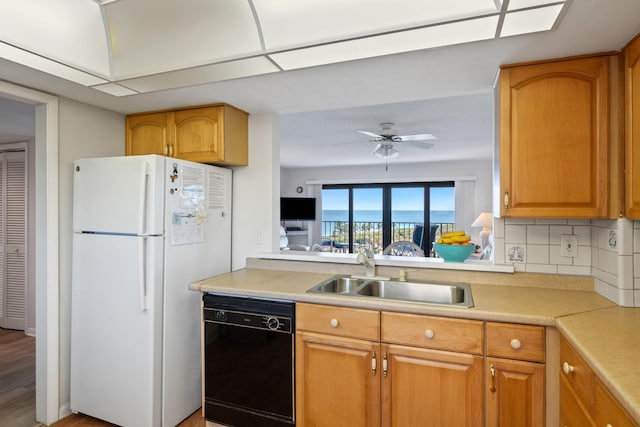 kitchen with light countertops, freestanding refrigerator, backsplash, a sink, and dishwasher