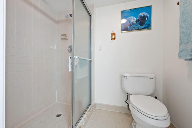 bathroom with baseboards, toilet, a stall shower, and tile patterned flooring