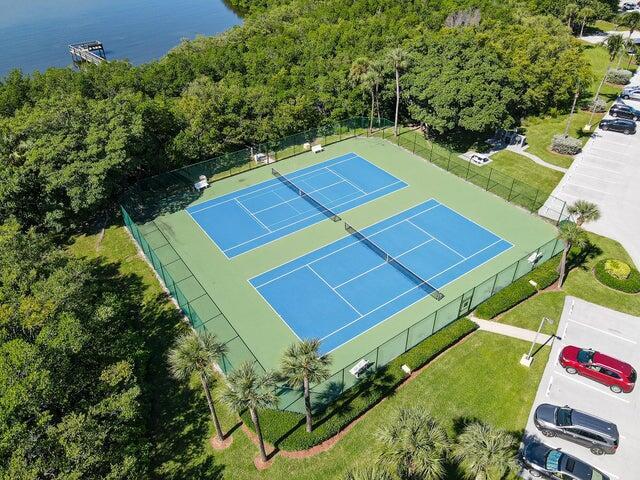 view of tennis court featuring a water view and fence