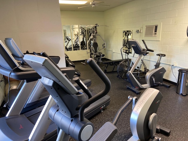 workout area with concrete block wall, a ceiling fan, and a wall unit AC