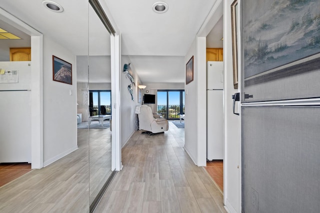 corridor featuring light wood-style flooring and baseboards