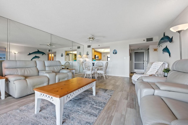 living room with wood finished floors, visible vents, a textured ceiling, and ceiling fan