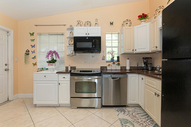 3899 Tuskegee Dr, Lake Worth, FL 33462 - kitchen with black appliances, white cabinets, light tile patterned floors, vaulted ceiling, and dark countertops