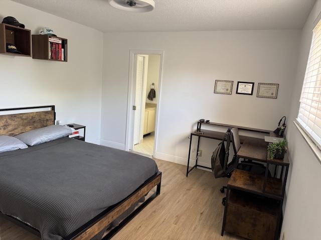 bedroom featuring baseboards, light wood-style floors, and ensuite bathroom