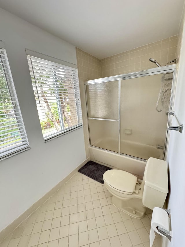 full bathroom with combined bath / shower with glass door, toilet, baseboards, and tile patterned floors