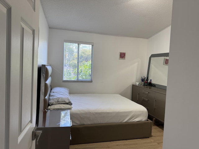 bedroom with light wood-type flooring and a textured ceiling
