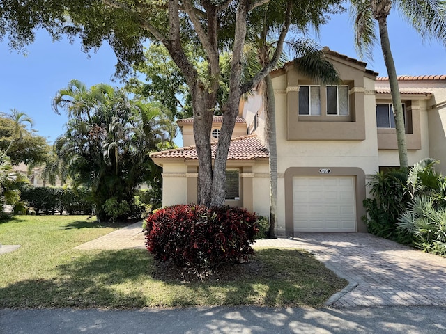 mediterranean / spanish-style home with stucco siding, an attached garage, decorative driveway, and a tiled roof