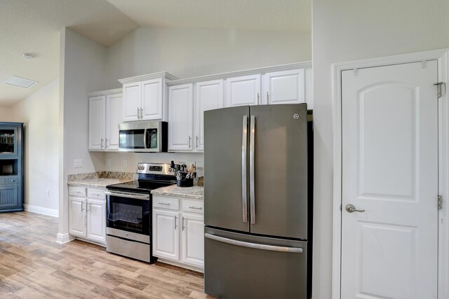 134 Day Dr, Sebastian, FL 32958 - kitchen with light wood finished floors, lofted ceiling, white cabinets, and stainless steel appliances