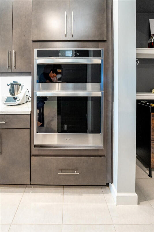 details featuring dark brown cabinets, light countertops, and stainless steel double oven