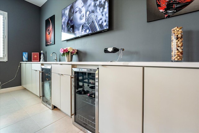 bar with baseboards, indoor wet bar, light tile patterned floors, and beverage cooler