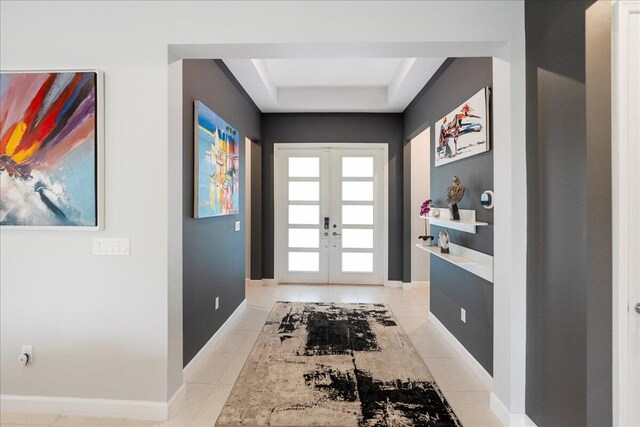 doorway to outside with french doors, a raised ceiling, light tile patterned flooring, and baseboards