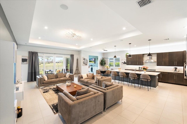 living area featuring light tile patterned floors, recessed lighting, a tray ceiling, and visible vents