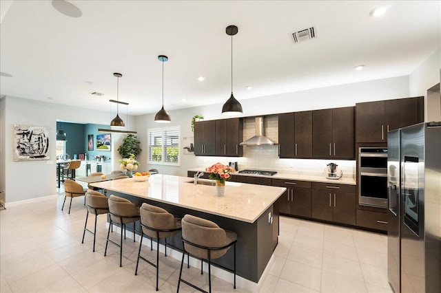 kitchen featuring tasteful backsplash, a breakfast bar area, stainless steel appliances, visible vents, and wall chimney exhaust hood