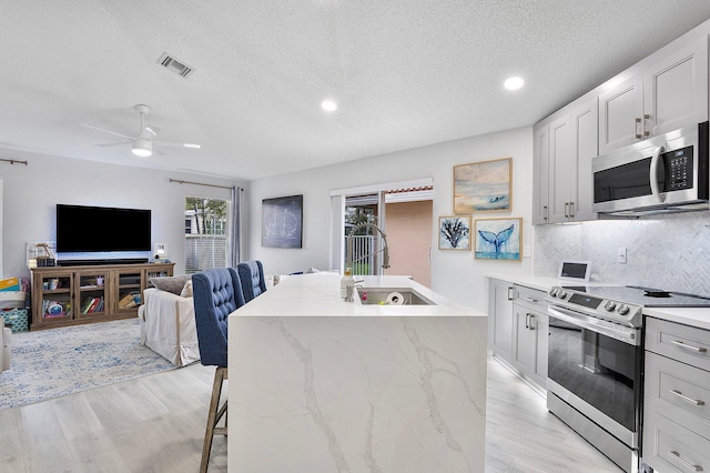 3773 NW 63rd Ct, Coconut Creek, FL 33073 - kitchen featuring visible vents, stainless steel appliances, a sink, light wood-style floors, and backsplash
