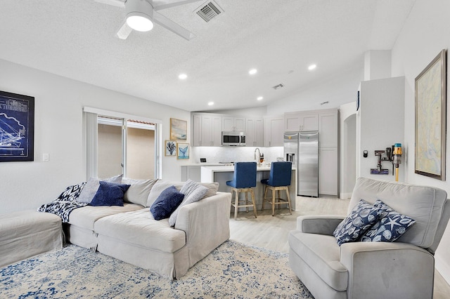 3773 NW 63rd Ct, Coconut Creek, FL 33073 - living area featuring a textured ceiling, visible vents, ceiling fan, light wood-type flooring, and vaulted ceiling