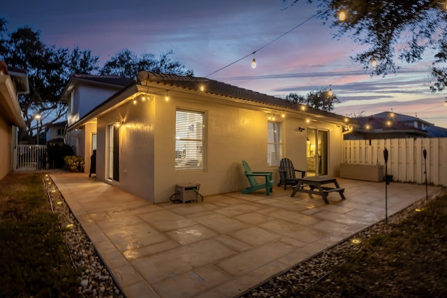 3773 NW 63rd Ct, Coconut Creek, FL 33073 - back of house at dusk with fence, stucco siding, and a patio