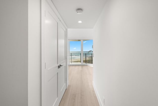 hall with light wood-type flooring and baseboards