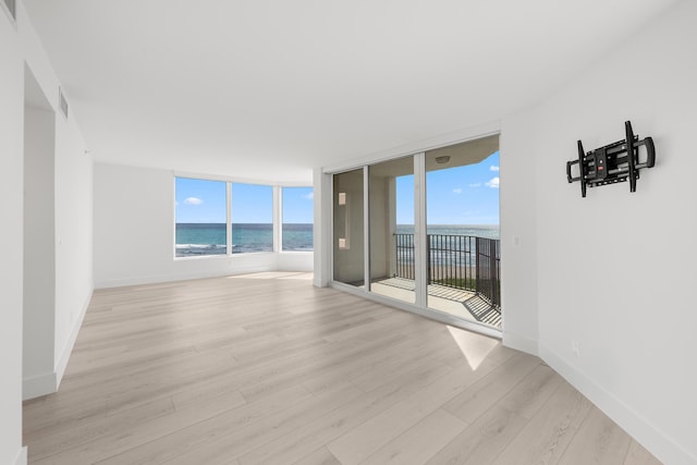 unfurnished room featuring a water view, baseboards, light wood finished floors, and visible vents