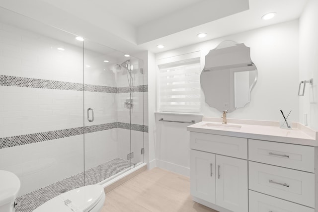 bathroom featuring toilet, wood finished floors, a shower stall, vanity, and recessed lighting