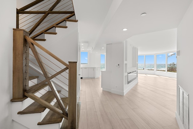 staircase with a water view, visible vents, a healthy amount of sunlight, and wood finished floors