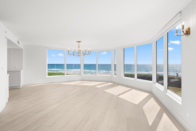 unfurnished sunroom featuring a water view, a chandelier, wood finished floors, and visible vents