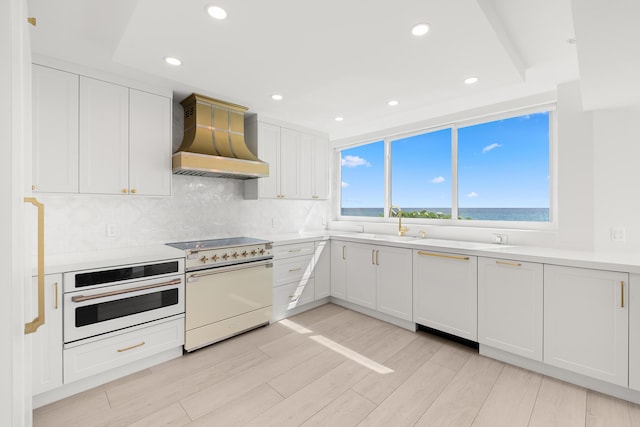 2575 S Ocean Blvd Unit 102S, Highland Beach, FL 33487 - kitchen featuring custom exhaust hood, white appliances, tasteful backsplash, white cabinetry, and light countertops