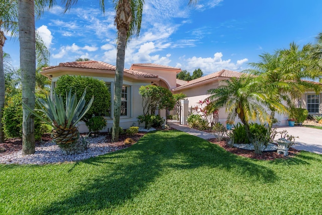 7406 Carmela Way, Delray Beach, FL 33446 - mediterranean / spanish house with a front yard, driveway, a tiled roof, an attached garage, and stucco siding