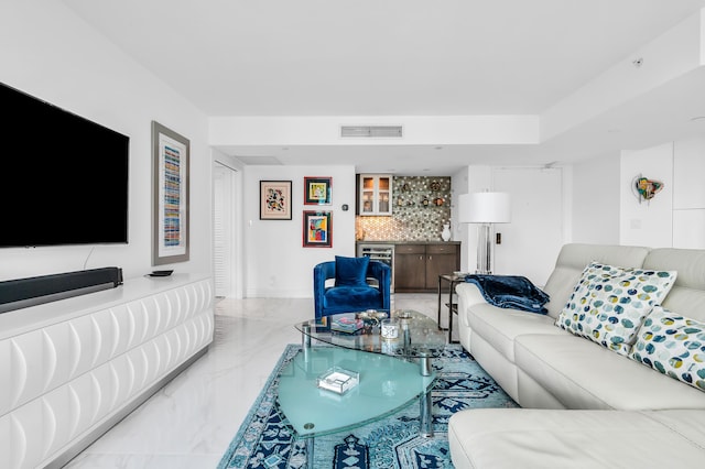 living area featuring marble tiled flooring, a bar, and baseboards