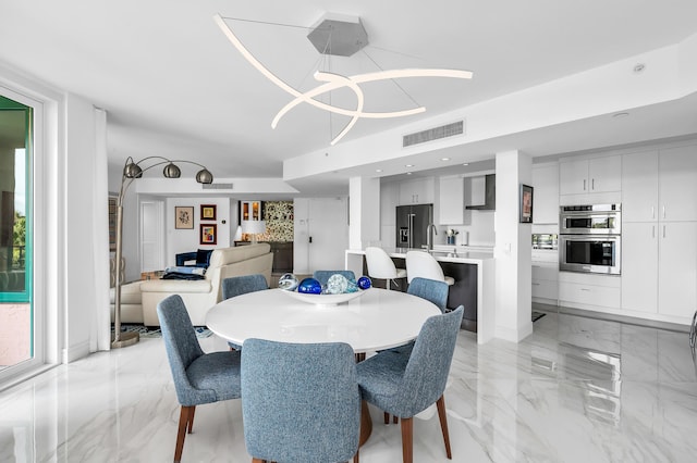 dining space featuring light marble finish floors, a chandelier, and plenty of natural light