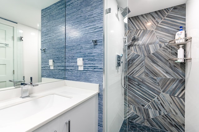 full bathroom featuring tiled shower, vanity, and tile walls