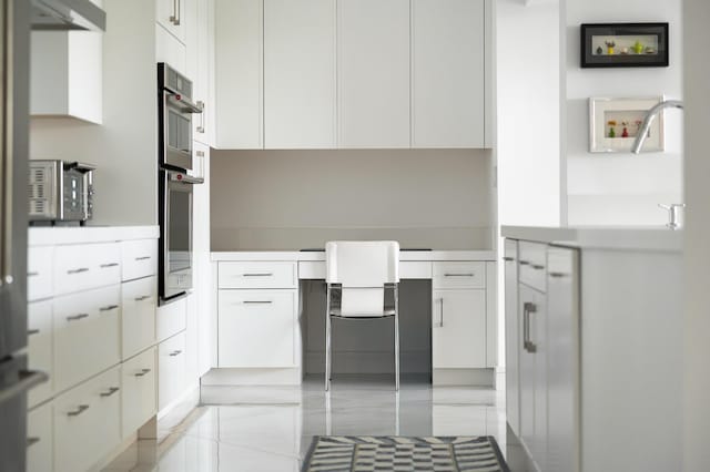 kitchen with white cabinetry, under cabinet range hood, and stainless steel double oven