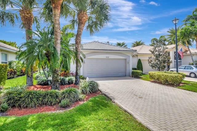 view of front of property with a garage, stucco siding, a tiled roof, and decorative driveway