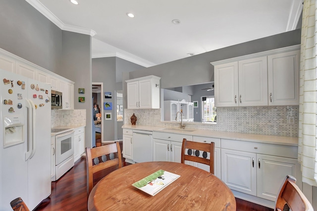 kitchen with white appliances, white cabinetry, ornamental molding, light countertops, and a sink