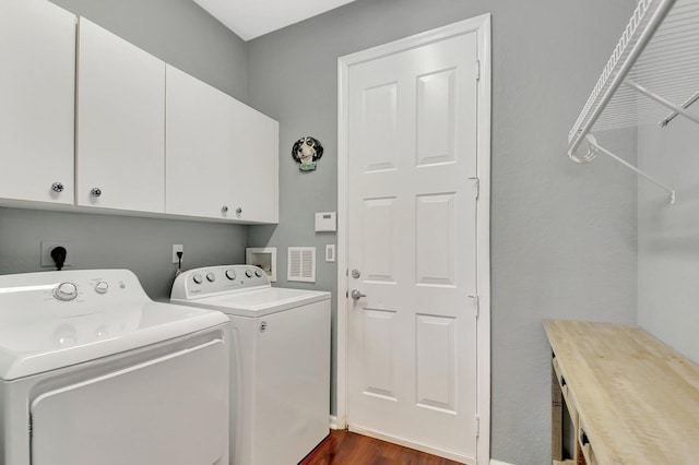 clothes washing area with dark wood finished floors, independent washer and dryer, and cabinet space