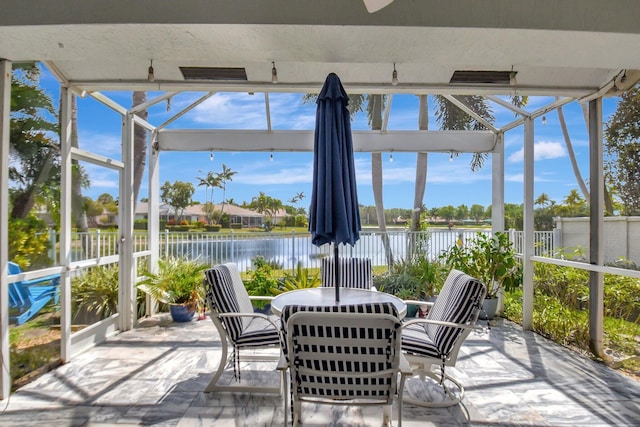 sunroom / solarium with a water view and outdoor dining space
