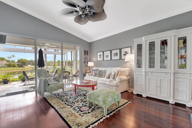 living area featuring dark wood-type flooring, ornamental molding, a ceiling fan, and vaulted ceiling