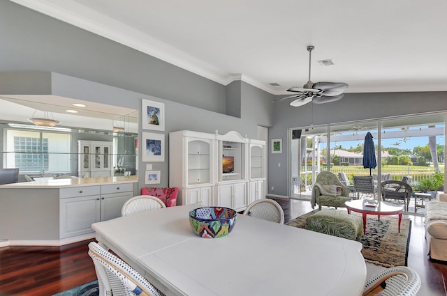 dining area with dark wood finished floors, ornamental molding, visible vents, a ceiling fan, and vaulted ceiling